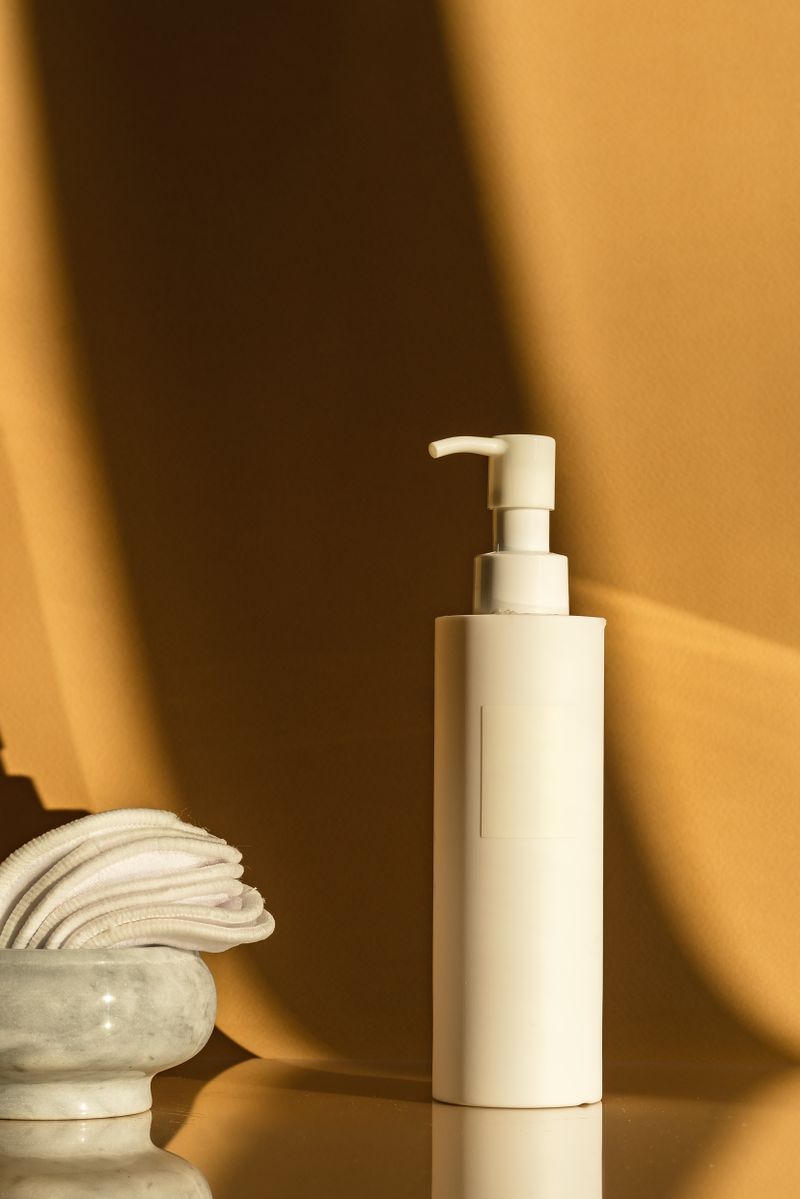 Flacon de cosmétique et cotons dans une lumière chaude